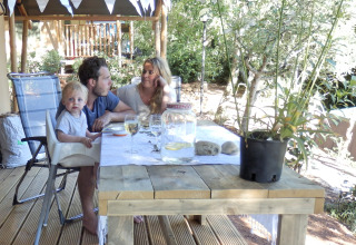 Gezin eet samen buiten onder safaritent op camping Rosselba le Palme in Italië, zonnige omgeving.