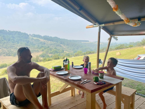 Familie genießt eine Mahlzeit im Safarizelt Lodgetent bei Les Terrasses de Dordogne Camping in Frankreich.