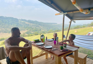 Famille partageant un repas dans une tente safari au camping Les Terrasses de Dordogne, en France.