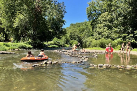Bambini giocano e fanno rafting in un fiume al campeggio La Prade, immerso nella natura in Occitania, Francia.