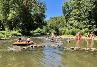 Bambini giocano e fanno rafting in un fiume al campeggio La Prade, immerso nella natura in Occitania, Francia.