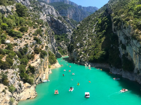 Persone in barca sull’acqua turchese, tra le scogliere, al campeggio La Digue in Francia.