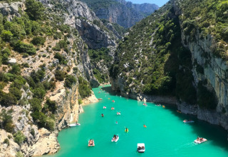 Persone in barca sull’acqua turchese, tra le scogliere, al campeggio La Digue in Francia.