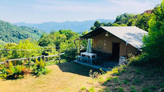 Safaritent premium plek nestled in lush hills, offering stunning views of the valley and surrounding mountains.