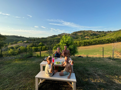 Gezin geniet buiten aan een picknicktafel van het uitzicht bij Agricampeggio Tasteria in Italië.