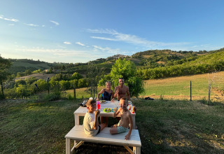 Gezin geniet buiten aan een picknicktafel van het uitzicht bij Agricampeggio Tasteria in Italië.