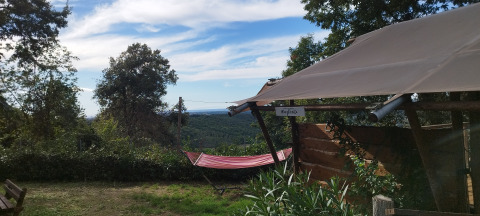 Zicht vanuit een safaritent met privébadkamer bij Agricampeggio La Prugnola, Italië, met hangmat en natuur.