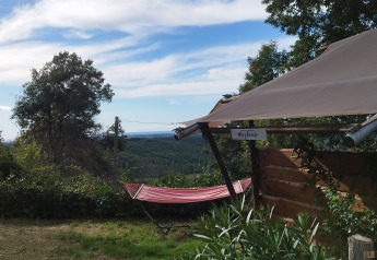 Vue d'une tente safari avec salle de bain privée à Agricampeggio La Prugnola, Italie, avec hamac et nature.