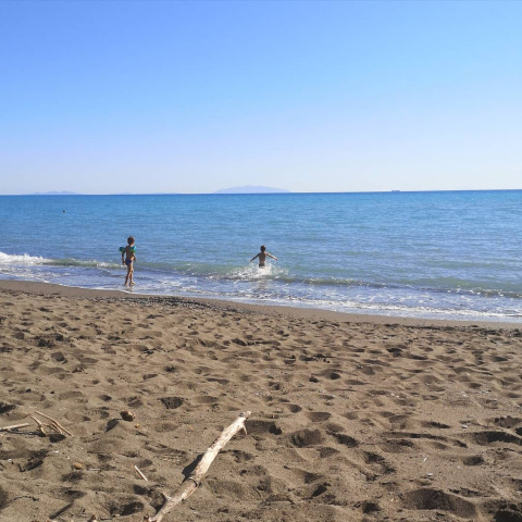 Kinderen spelen aan het strand bij de safaritent met privébadkamer op Agricampeggio La Prugnola in Italië.