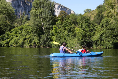 Due persone in kayak su un fiume circondato da alberi e scogliere presso un parco vacanze glamping.