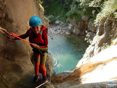 Persona con casco e giubbotto di salvataggio arrampicata su parete rocciosa al Campeggio Belvedere, Lombardia, Italia.