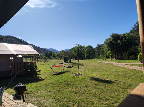 Aussicht von der Lodgetent XL mit Bad auf dem Campingplatz Le Moulin de Cost, umgeben von Natur in Frankreich.