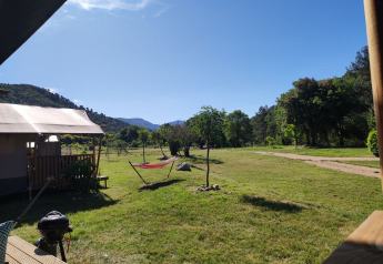 Vista desde la tienda Lodgetent XL con baño en el camping Le Moulin de Cost, rodeada de naturaleza en Francia.