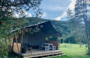 Safari tent Lodgetent XL with bathroom at Campsite La Faz in France, surrounded by lush, green hills.