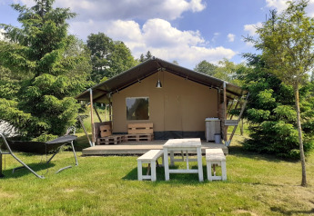 Safari telt ved Campsite Les Trexons i Frankrig med træmøbler og grønne omgivelser under blå himmel.