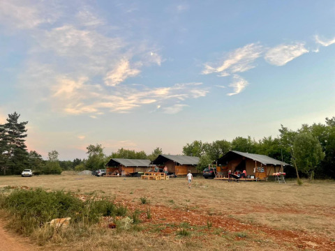 Safari-telte ved Domaine de Pradines i Frankrig med aftenhimmel og åbent område foran teltene.