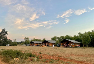 Safari-telte ved Domaine de Pradines i Frankrig med aftenhimmel og åbent område foran teltene.