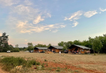 Tiendas safari en Domaine de Pradines, Francia, con campo abierto y cielo vespertino sobre las tiendas.