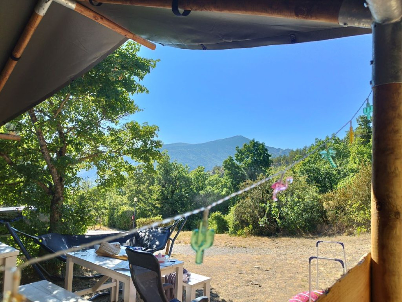 Uitzicht vanuit een safaritent bij Domaine Les 2 Soleils in Frankrijk, met tafels en bergen.