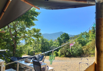 Vista desde una tienda safari en Domaine Les 2 Soleils, Francia, con mesas y montañas al fondo.