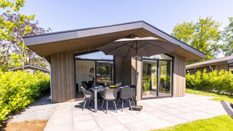 Moderno lodge Villa Waterzicht Luxe con sauna, ampia terrazza, arredi da esterno e ombrellone.
