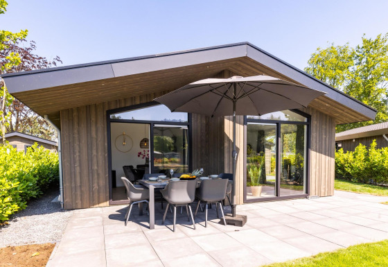 Moderna casa Villa Waterzicht Luxe con sauna, terraza amplia, muebles de jardín y sombrilla grande.