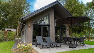 Outdoor view of Ecovilla Waterzicht Comfort Sauna & Buitendouche featuring patio, loungers, and umbrella.