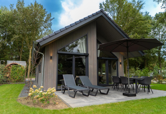Outdoor view of Ecovilla Waterzicht Comfort Sauna & Buitendouche featuring patio, loungers, and umbrella.