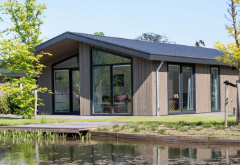 Moderne Villa Waterzicht Luxe 4 Lodge am Wasser mit großen Fenstern und Garten an einem sonnigen Tag