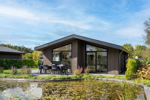 Lodge moderna chiamata Villa Waterzicht Luxe met Ligbad con patio e vista stagno in una giornata di sole