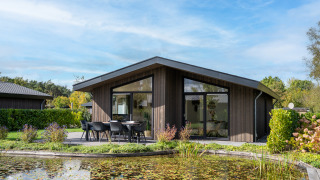 Lodge moderne Villa Waterzicht Luxe met Ligbad avec terrasse et vue sur l’étang par une journée ensoleillée