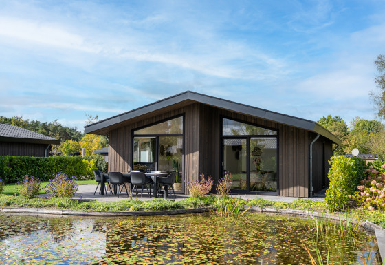 Lodge moderna chiamata Villa Waterzicht Luxe met Ligbad con patio e vista stagno in una giornata di sole
