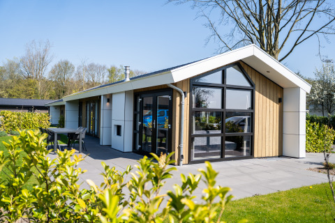 Moderne hytte i træ og glas med terrasse og have, set fra siden, beliggende ved Wood Lodge Waterzicht.