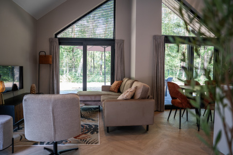 Chic living area at Ecovilla Waterzicht Luxe in Holiday park Latour, overlooking the lush green forest.