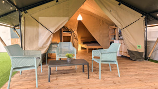 Safari tent met toilet, moderne meubels, houten terras en comfortabel bed in een gezellige, luxe sfeer.
