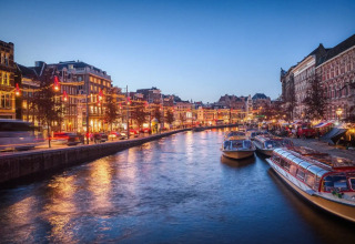 Vue du soir sur un canal avec bateaux illuminés et bâtiments historiques près d’Uitgeest, Hollande du Nord.