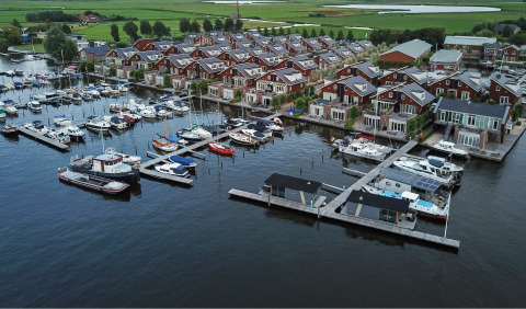 Luftfoto af Marina Uitgeest feriepark i Nordholland, Nederlandene, med hytter og både langs vandet.