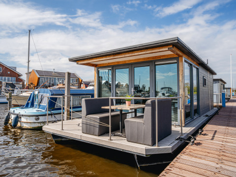 Modern floating holiday home at Marina Uitgeest, North Holland, Netherlands, with outdoor seating and view.