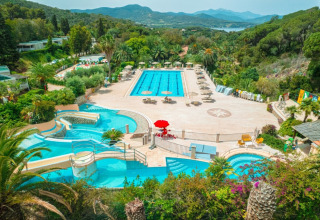 Vue du camping Rosselba le Palme en Toscane avec piscines, palmiers et magnifique paysage environnant.