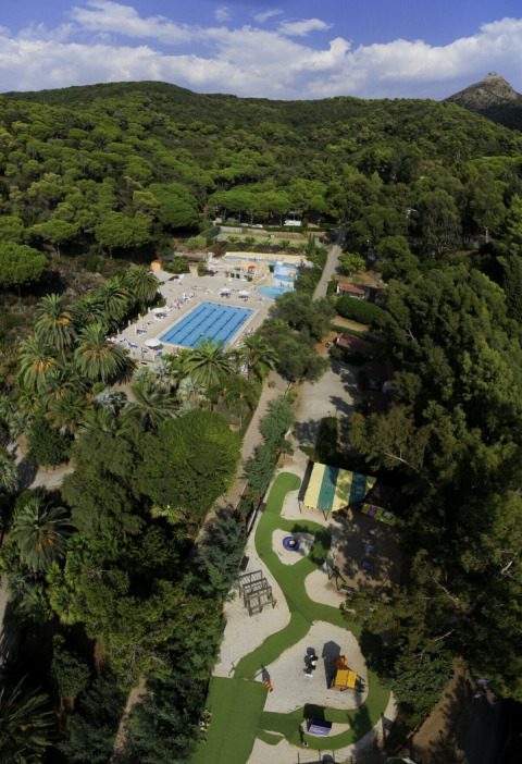 Aerial view of Campsite Rosselba le Palme in Tuscany, Italy, featuring pools and lush green forest.