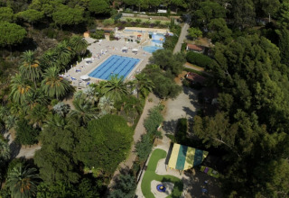 Aerial view of Campsite Rosselba le Palme in Tuscany, Italy, featuring pools and lush green forest.