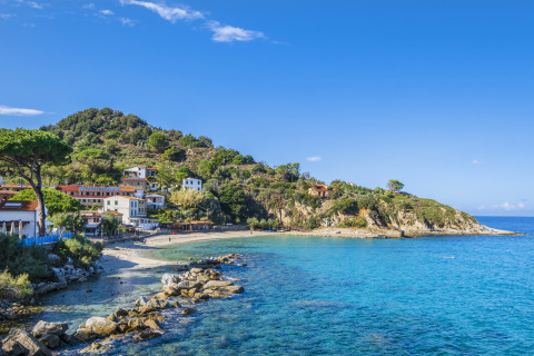 Coastal scenery near Portoferraio, Tuscany, Italy, featuring clear blue waters and hillside homes.