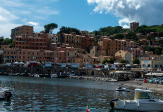 View of Rosselba le Palme campsite harbor in Tuscany, Italy, featuring boats and colorful hillside houses.