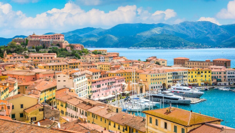 Vista su Portoferraio in Toscana, Italia, con edifici colorati, porto turistico e colline sullo sfondo.