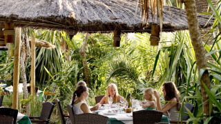 Udendørs restaurantområde omgivet af palmer på Campsite Rosselba le Palme, en feriepark i Toscana, Italien.