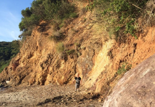 Child walking along a rocky path at the base of a steep hill at Campsite Rosselba le Palme, Tuscany, Italy, in sunlight.