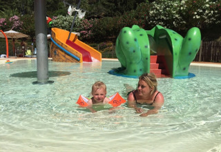 Un bambino e una donna nuotano nella piscina bassa del campeggio Rosselba le Palme in Toscana, Italia.