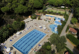 Aerial view of Campsite Rosselba le Palme in Tuscany, Italy, featuring pools surrounded by lush greenery.