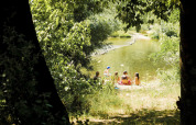 En gruppe mennesker slapper af ved en flod omgivet af træer på Campsite La Plage i Occitanie, Frankrig.