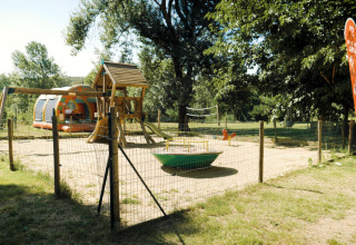 Legeplads med gynger og rutsjebane på campingpladsen La Plage i Occitanie, Frankrig, omgivet af grønne træer.